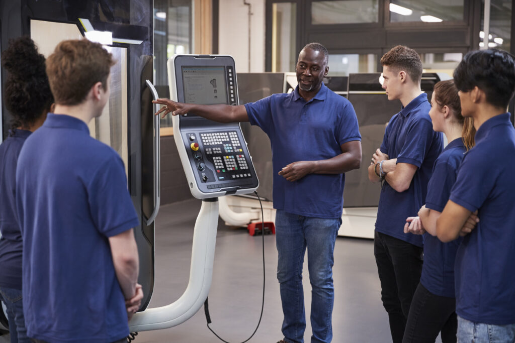 Engineer Showing Apprentices How To Use CNC Tool Making Machine